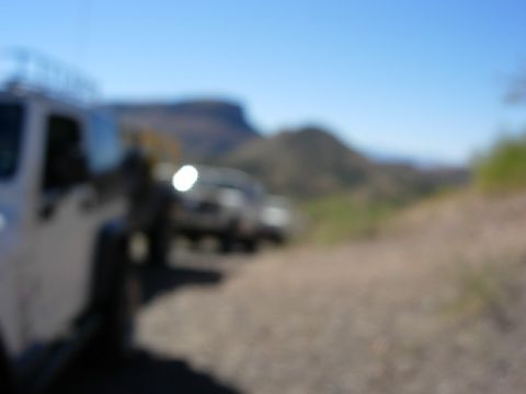 1981 Ford F-150 - Two vehicles are parked on a dirt road with a mountainous landscape under a clear blue sky.