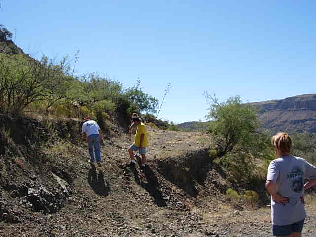 People walking on a dirt path in a dry, hilly landscape