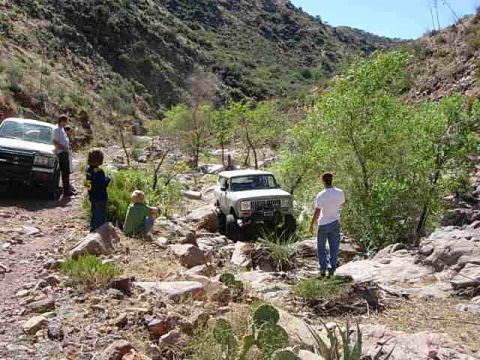 1981 Ford F-150 - A group of people and two off-road vehicles navigate a , rocky canyon trail.