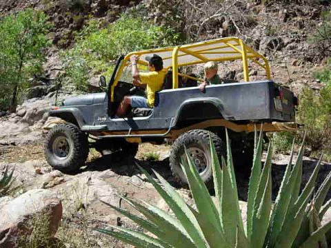 1981 Ford F-150 - Two people are riding in a Jeep CJ-7 as it navigates a rocky, off-road trail.