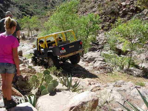 1981 Ford F-150 - A Jeep CJ-7 with a yellow roll cage is driven off-road on a , rocky trail.