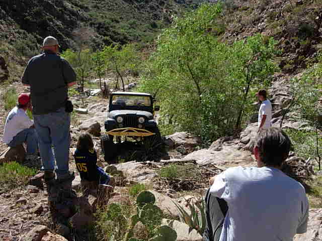 Jeep CJ-7 on rocky trail with people watching