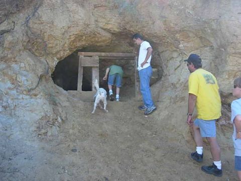 1981 Ford F-150 - A group of people and a dog are gathered near the entrance of a cave.