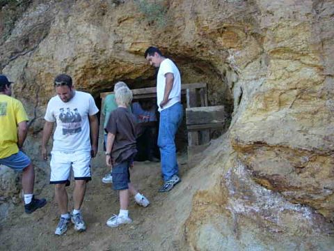 1981 Ford F-150 - Several individuals are gathered around the entrance of a mine, with a wooden structure visible inside the opening.