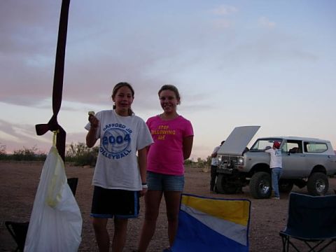 1981 Ford F-150 - Two girls stand in front of an off-road vehicle with its hood up, in a desert-like setting at dusk.