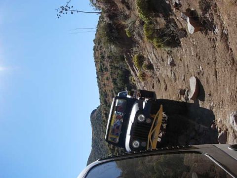 1981 Ford F-150 - Jeep CJ-7 navigating a challenging off-road trail with steep terrain.