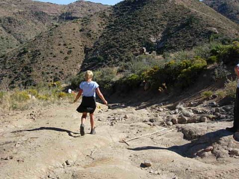 1981 Ford F-150 - A person walks down a dirt path in a dry, mountainous landscape.