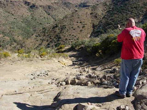 1981 Ford F-150 - A person surveys a , arid landscape with hills and a dry creek bed.