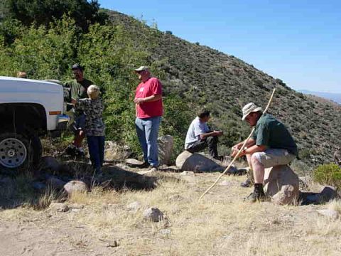 1981 Ford F-150 - A group of people are gathered near a white truck on a dry, grassy hillside under a clear blue sky.