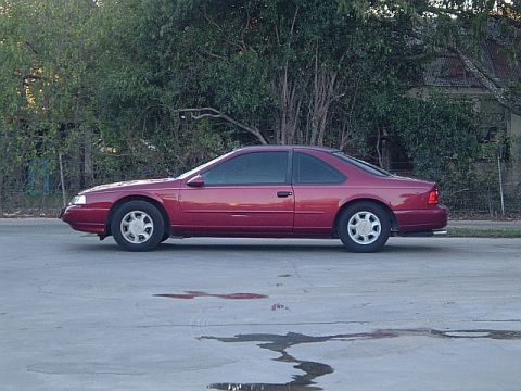 1994 Ford Thunderbird - Side profile of a red 1994 Ford Thunderbird coupe parked on a street.