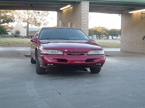 1994 Ford Thunderbird - A red 1994 Ford Thunderbird coupe is parked under a covered area.