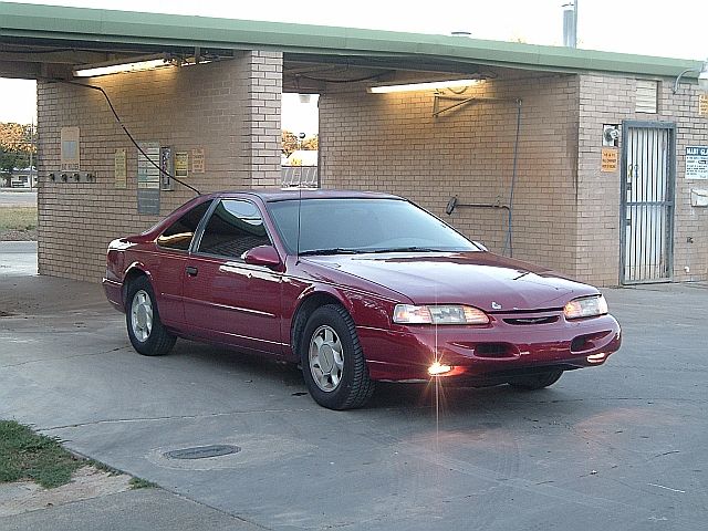 Red 1994 Ford Thunderbird coupe parked outside a brick building