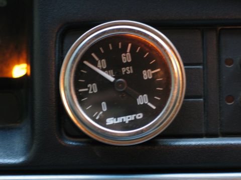 1995 Ford Bronco - A close-up of a Sunpro oil pressure gauge mounted on a vehicle's dashboard.