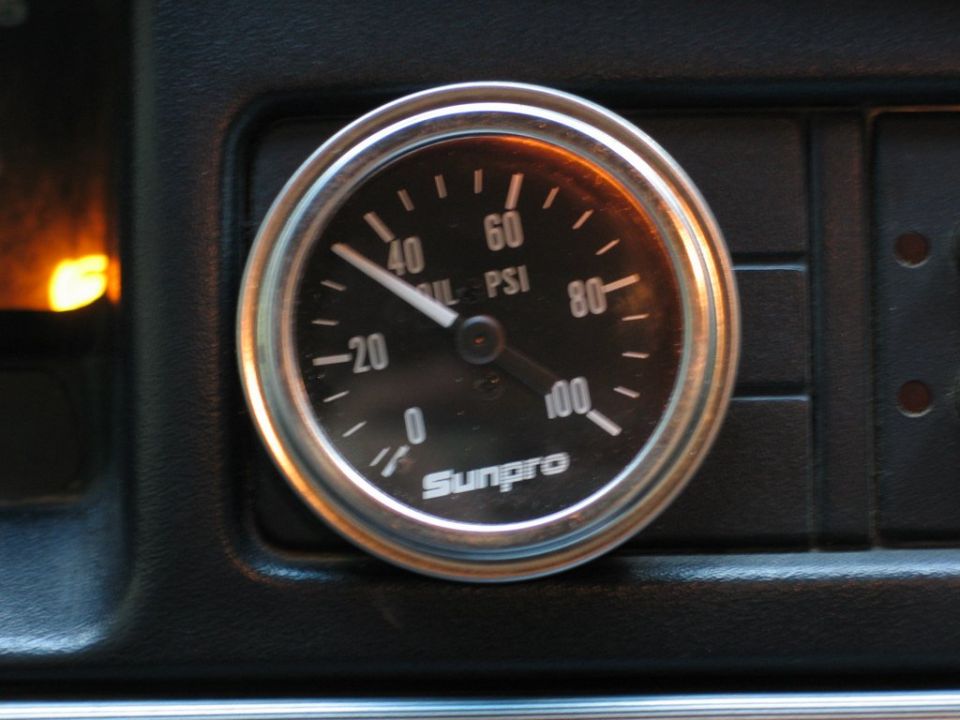 Sunpro oil pressure gauge with needle pointing to 30 PSI, set in black dashboard