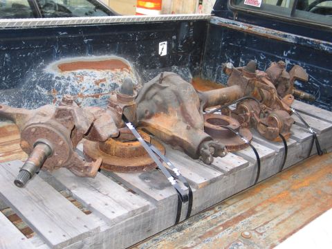 1995 Ford Bronco - Two front axle assemblies and brake rotors are secured to a wooden pallet in the bed of a pickup truck.