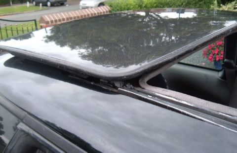 1994 Ford Probe - The reflective sunroof of a car is shown, with a glimpse of the interior and other vehicles outside.