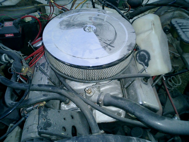 Engine bay with chrome air cleaner, hoses, and a white fluid reservoir. The condition appears used