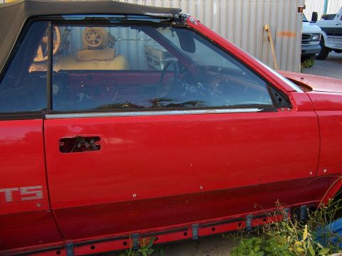 1984 Toyota Celica - This red convertible sports car appears to be a project or parts car, with its interior exposed and some exterior damage.