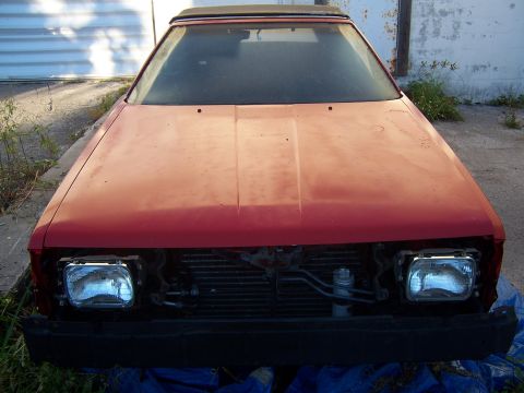 1984 Toyota Celica - Front view of a red 1984 Toyota Celica, appearing to be a project or parts car, with its grille and headlights removed.