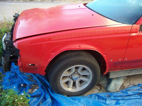 1984 Toyota Celica - Front quarter panel and wheel of a red 1984 Toyota Celica project car.