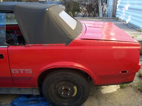1984 Toyota Celica - This red convertible shows the rear quarter panel and soft top, with 'GTS' badging visible.
