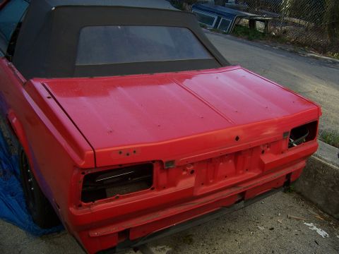 1984 Toyota Celica - This red convertible's rear end is visible, showing missing bumper and taillight assemblies, consistent with a 1984 Toyota Celica.