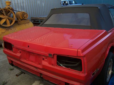 1984 Toyota Celica - Rear view of a red 1984 Toyota Celica convertible project car, missing its bumper and taillights.