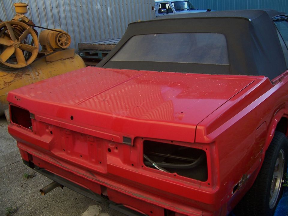 Rear view of a red 1984 Toyota Celica convertible project car with the bumper removed