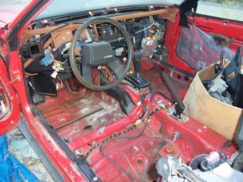 1984 Toyota Celica - The interior of a red 1984 Toyota Celica shows extensive disassembly, with wiring exposed and the dashboard removed.