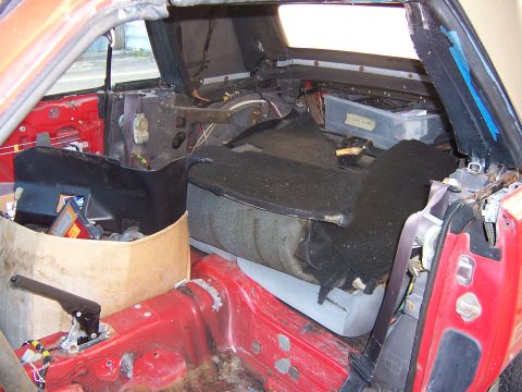 1984 Toyota Celica - The interior of a red 1984 Toyota Celica shows a stripped-down cabin with seats removed and various parts in disarray.