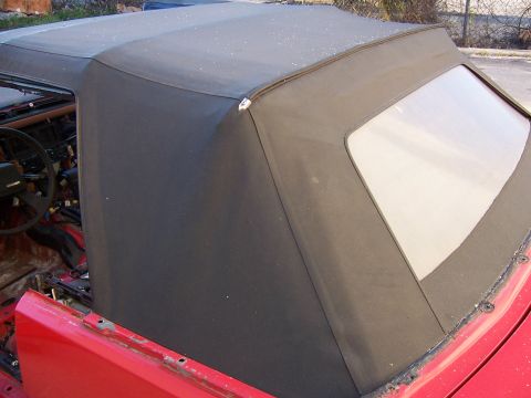 1984 Toyota Celica - Close-up of a car's convertible top and interior, with a red body panel visible.