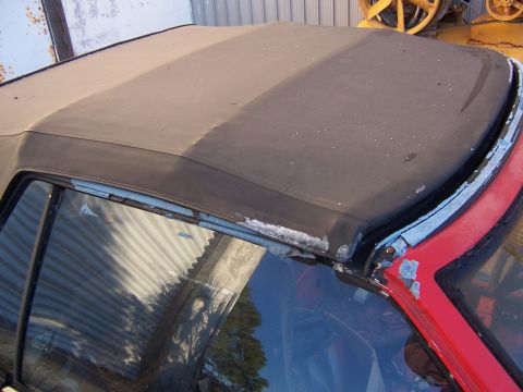 1984 Toyota Celica - The convertible top of a car shows significant wear and tear around the frame.