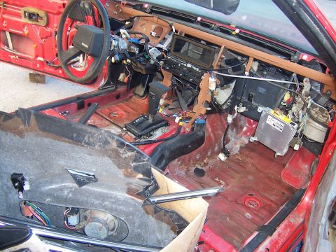 1984 Toyota Celica - The interior of a red car shows significant disassembly, with wiring and components exposed.