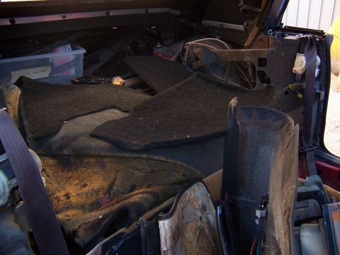 1984 Toyota Celica - The interior of a car is shown with its carpeting removed and various parts scattered around, suggesting a project or parts car.