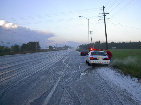 1985 Mercury Grand Marquis - A police car and a red car are stopped on a debris-covered road, possibly after an incident.