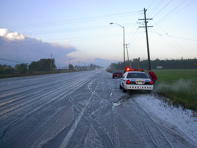White police Crown Victoria on a snowy roadside shoulder with light bar lit