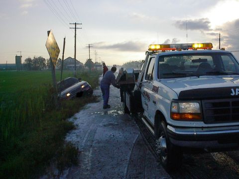 1985 Mercury Grand Marquis - Tow truck helping a car that slid off the road into a ditch.