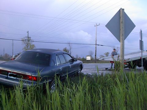 1985 Mercury Grand Marquis - A blue sedan is being loaded onto a tow truck after going off the road.