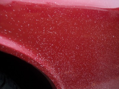 1972 Ford Ranchero - Close-up of a red car fender showing numerous white specks, possibly from road debris or paint imperfections.