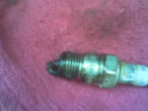 1986 Ford Bronco - Close-up of a used spark plug, showing wear on the electrode and threaded base.