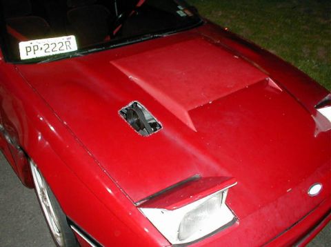 1992 Ford Probe - The front of a red car is shown, a custom hood scoop and a visible drive belt.