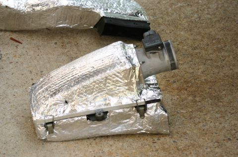 1994 Ford Bronco - A foil-insulated air intake tube/airbox assembly with a black plastic mass air flow (MAF) sensor and duct, laid on a concrete garage floor.…