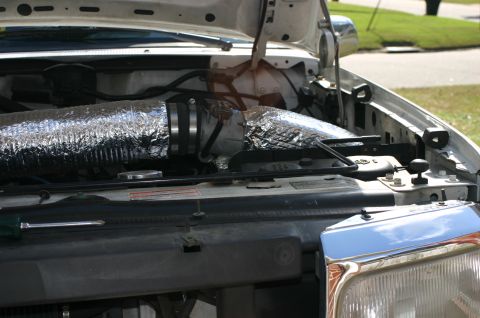 1994 Ford Bronco - Engine bay of a white Ford Bronco with the hood open, showing a custom cold-air intake made from silver flexible ducting (foil insulated fl…
