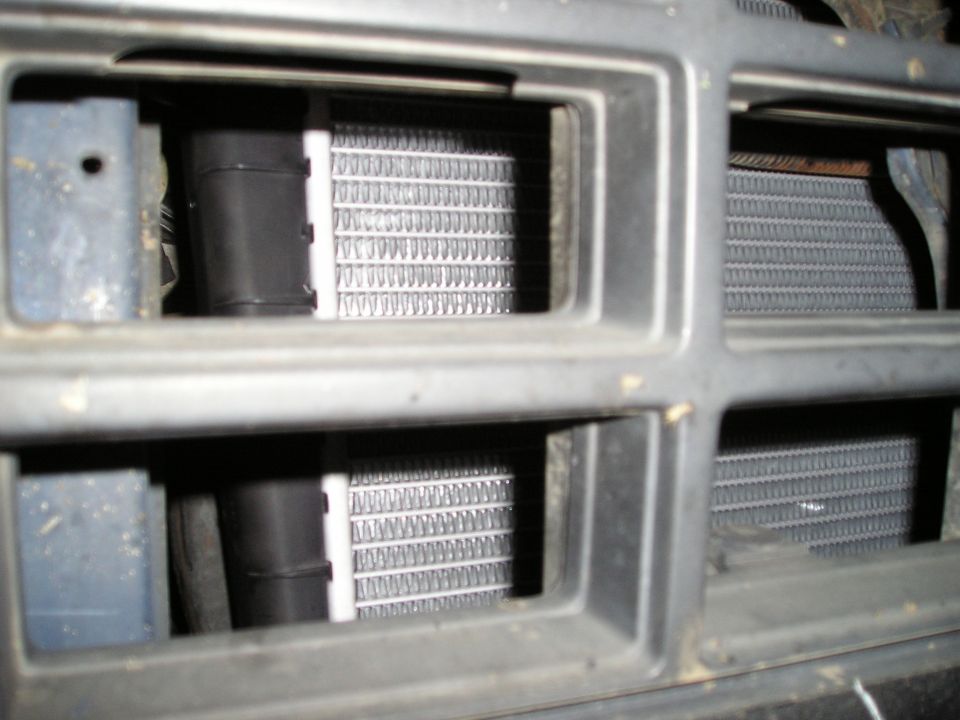 Radiator fins visible through a gray grille with black plastic components