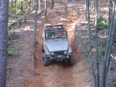 2004 Jeep Wrangler - A silver Jeep Wrangler navigates an off-road trail in a wooded area.