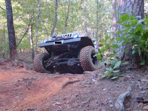 2004 Jeep Wrangler - A Jeep Wrangler navigates a challenging off-road trail with steep inclines and loose dirt.