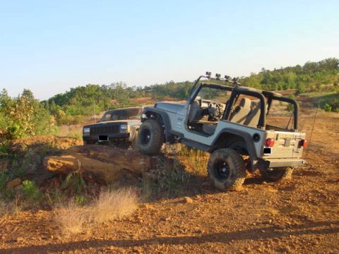 2004 Jeep Wrangler - Two Jeeps navigate a challenging off-road course on a sunny day.