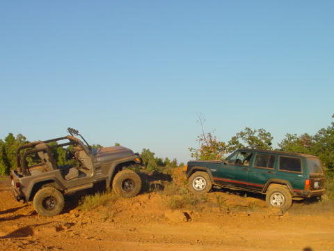 2004 Jeep Wrangler - Two Jeeps navigate a dirt trail under a clear blue sky.