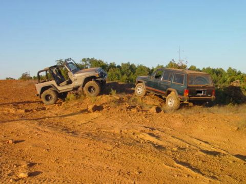 2004 Jeep Wrangler - Two Jeeps navigate a challenging off-road course under a clear blue sky.