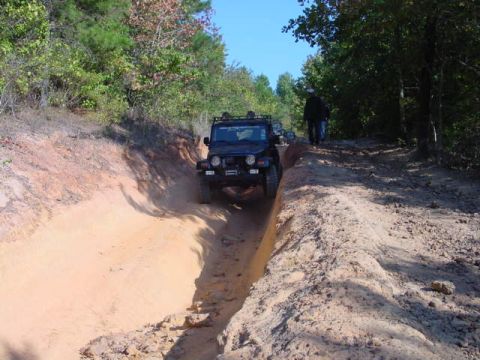 2004 Jeep Wrangler - A black Jeep TJ navigates a challenging dirt trail with another vehicle visible behind it.